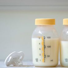 Two bottles of pumped breast milk alongside a pacifier.