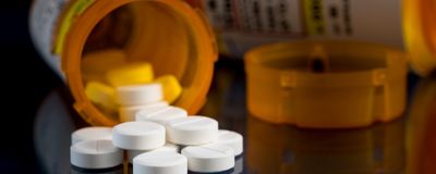 Oxycodone pill bottles on a table with one of the bottles tipped over and overflowing.