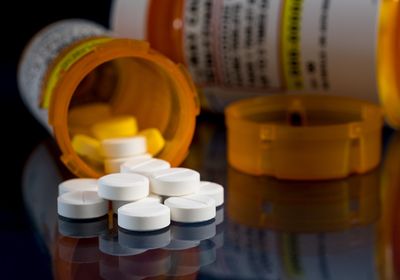 Oxycodone pill bottles on a table with one of the bottles tipped over and overflowing.&nbsp;