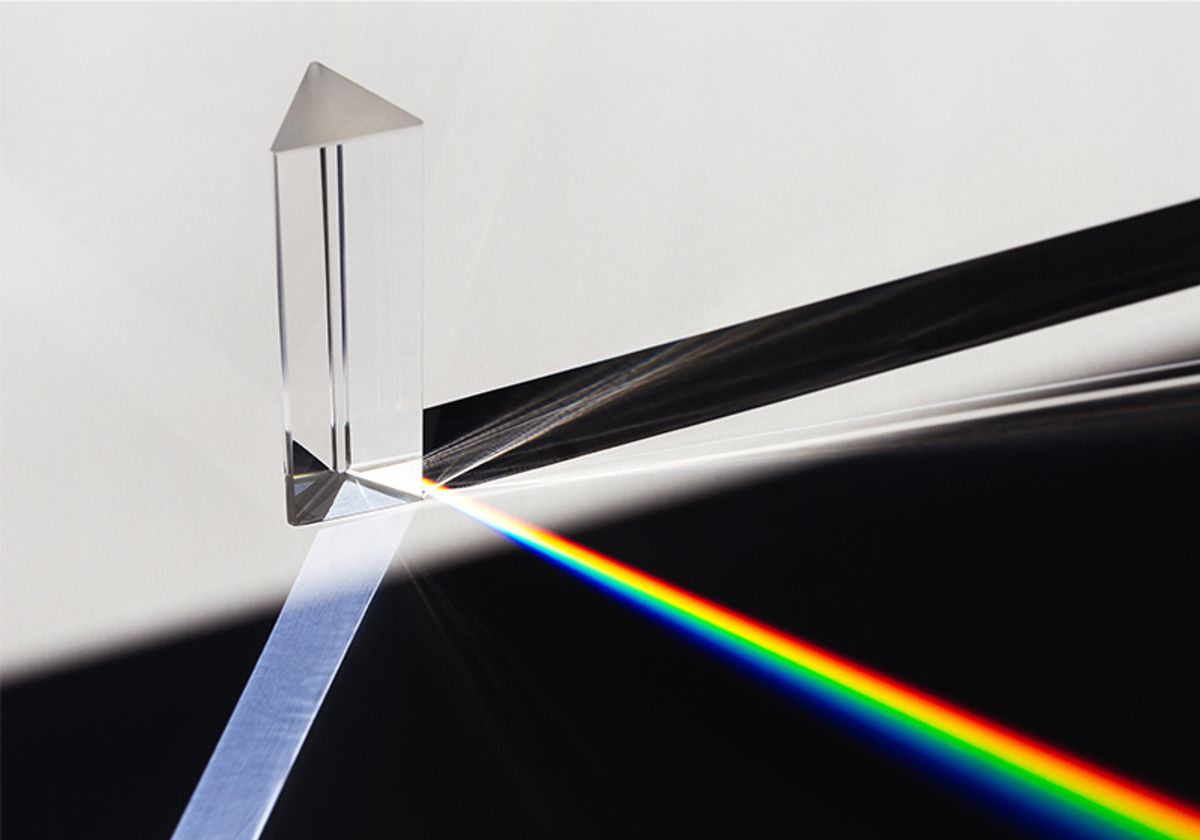 A prism dispersing sunlight, splitting into a spectrum on a white background.