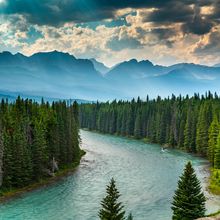 A river surrounded by trees with mountains in the background.