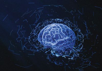 A rendering of a human brain in blue on a dark background with blue and white lines surrounding the brain to represent the construction of new connections in the brain.