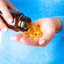 Closeup of a person pouring several dietary supplement capsules into their open palm.