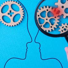 Two drawn heads on a blue background with gears in their heads. A red spot on two gears is magnified over one head.