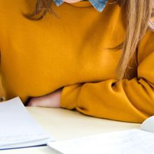 A person sitting in a laboratory writing notes with a pen in a notebook.