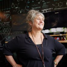 smiling woman with hands on hips with blackboard in background