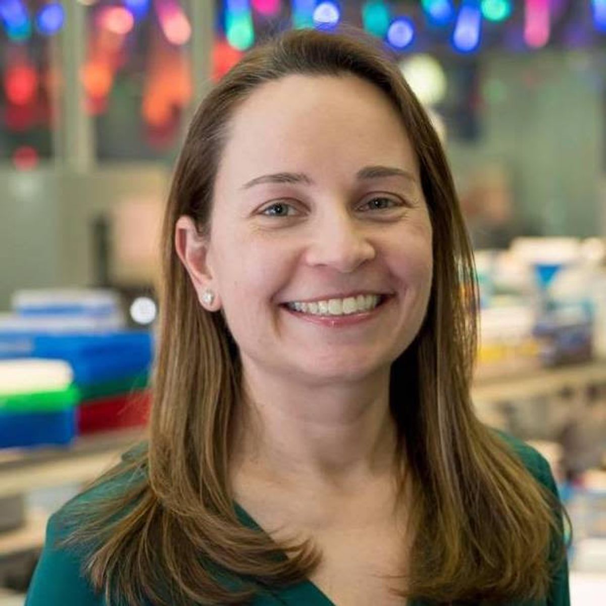 Julie Horvath smiles against a background of laboratory equipment.