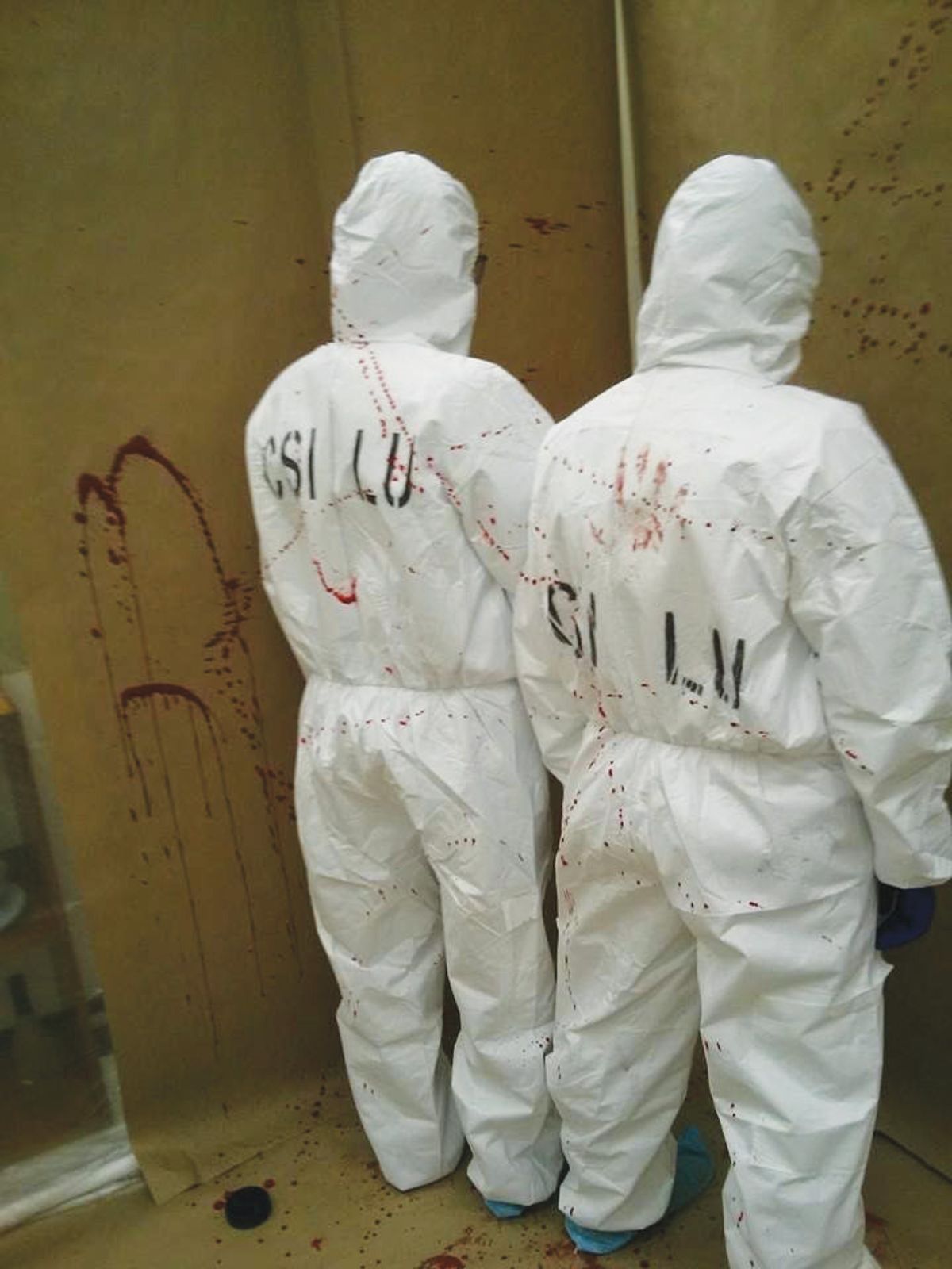 Image of Melissa and a classmate wearing white bunny suits in a blood spatter lab.