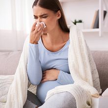 A pregnant woman blowing her nose.