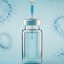 A syringe inserted into a vial of vaccine.