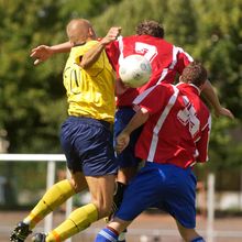 Three men collide while playing soccer