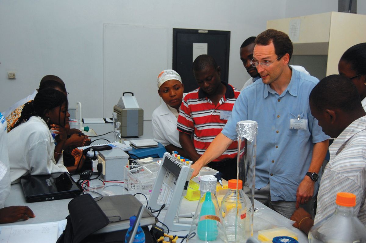 A group of people in a laboratory. Lab equipment is seen on the bench.