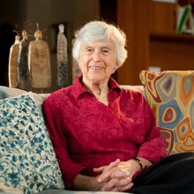 Woman in red shirt sitting on sofa, looking at camera