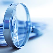 magnifying glass in front of a stack of paper