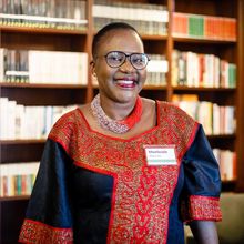 smiling woman against a backdrop of bookshelves