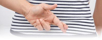 A woman in a blue and white striped shirt crosses her fingers behind her back.