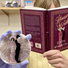 Bacteriologist Melinda Grosser holds the book <em >House of Mirth&nbsp;</em>by Edith Wharton and an agar art plate that recreates the book cover.